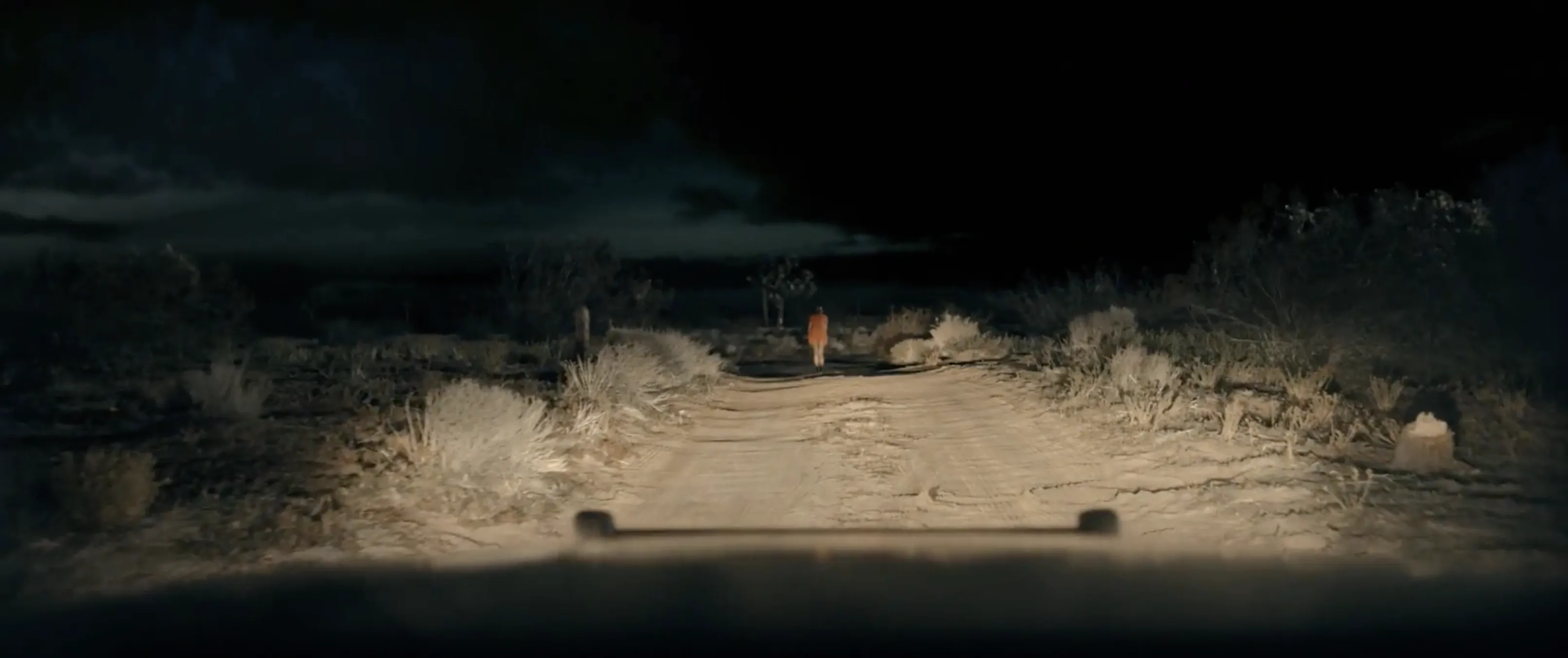 A night exterior cinematography frame from Blood Star, lit by headlights on a desert road