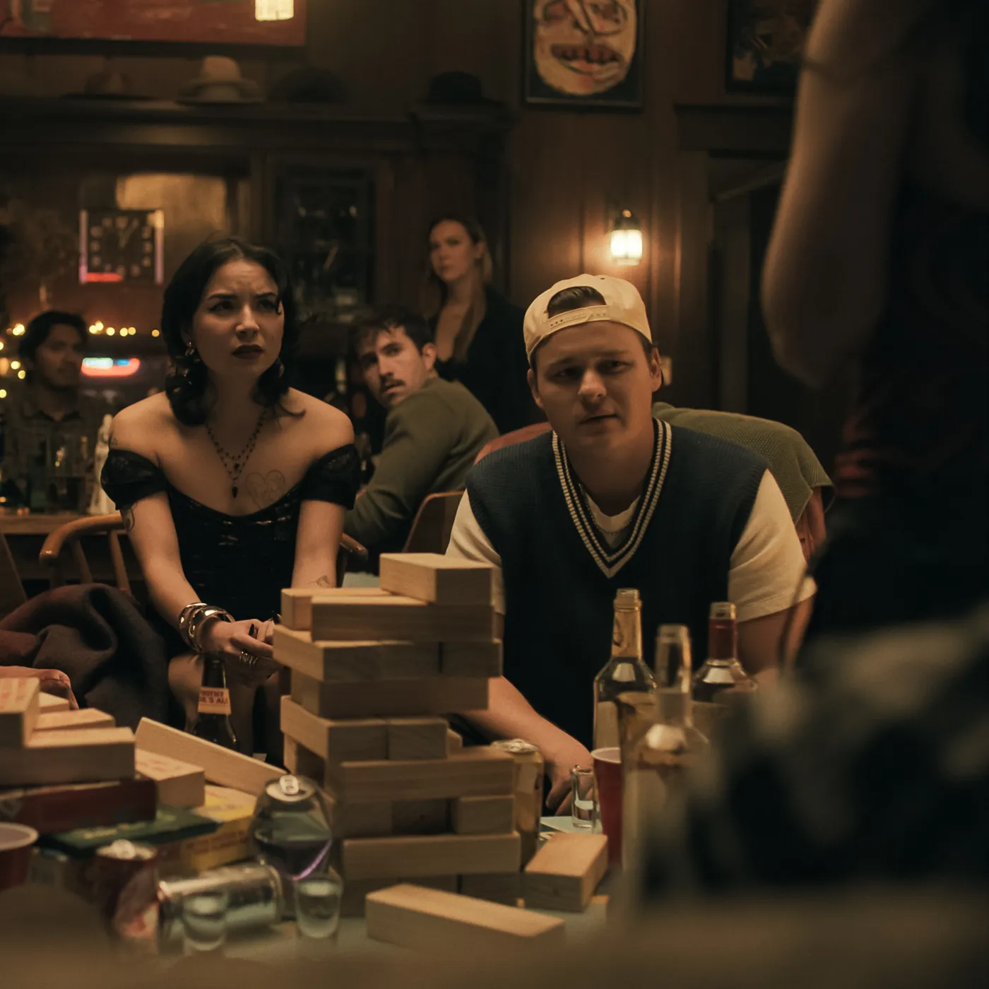 The friend group playing giant Jenga and drinking together at a bar
