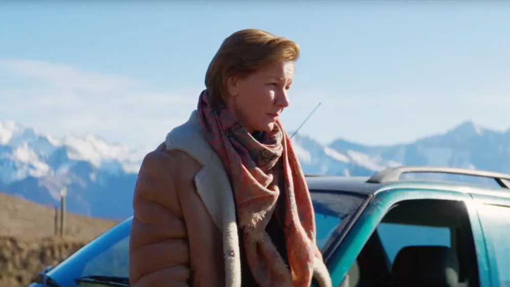 Sandra standing beside a car with snow-covered Alps behind her in Anatomy of a Fall (2023)