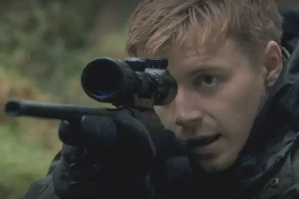 A hunter aiming a rifle through a scope in the Scottish Highlands in Calibre