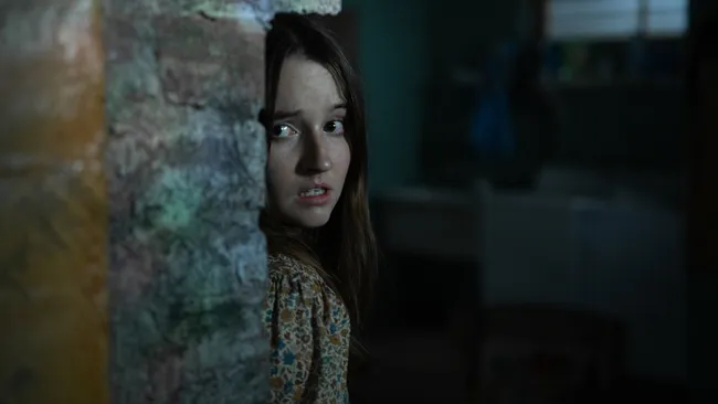 A woman holding a flashlight in a dark, cramped mobile-home bathroom in You'll Never Find Me (2023)
