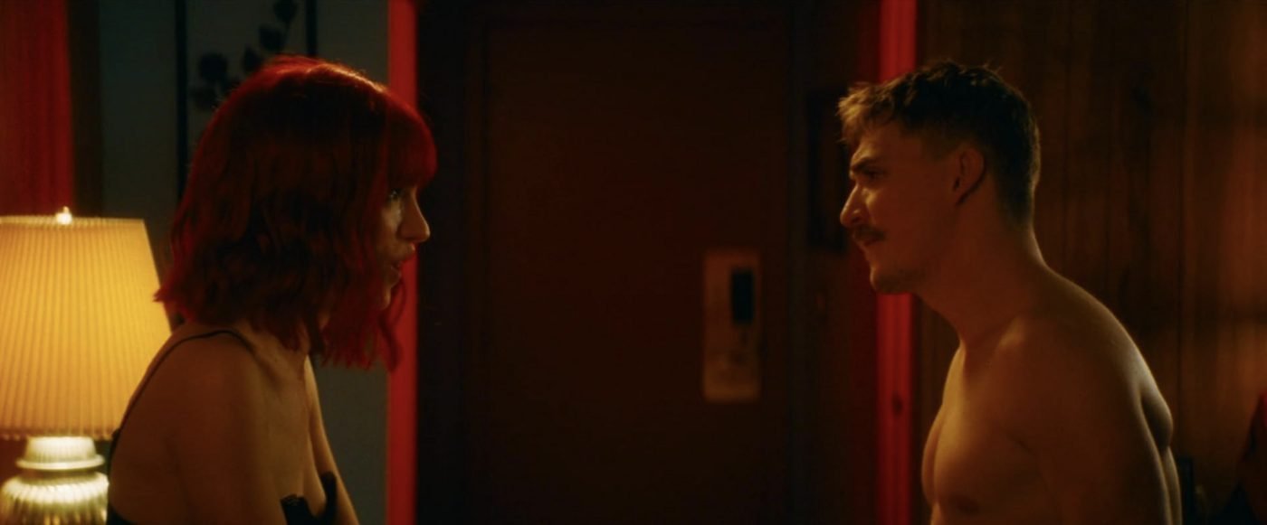 The Lady and the Demon standing face to face in a dimly lit motel room in Strange Darling