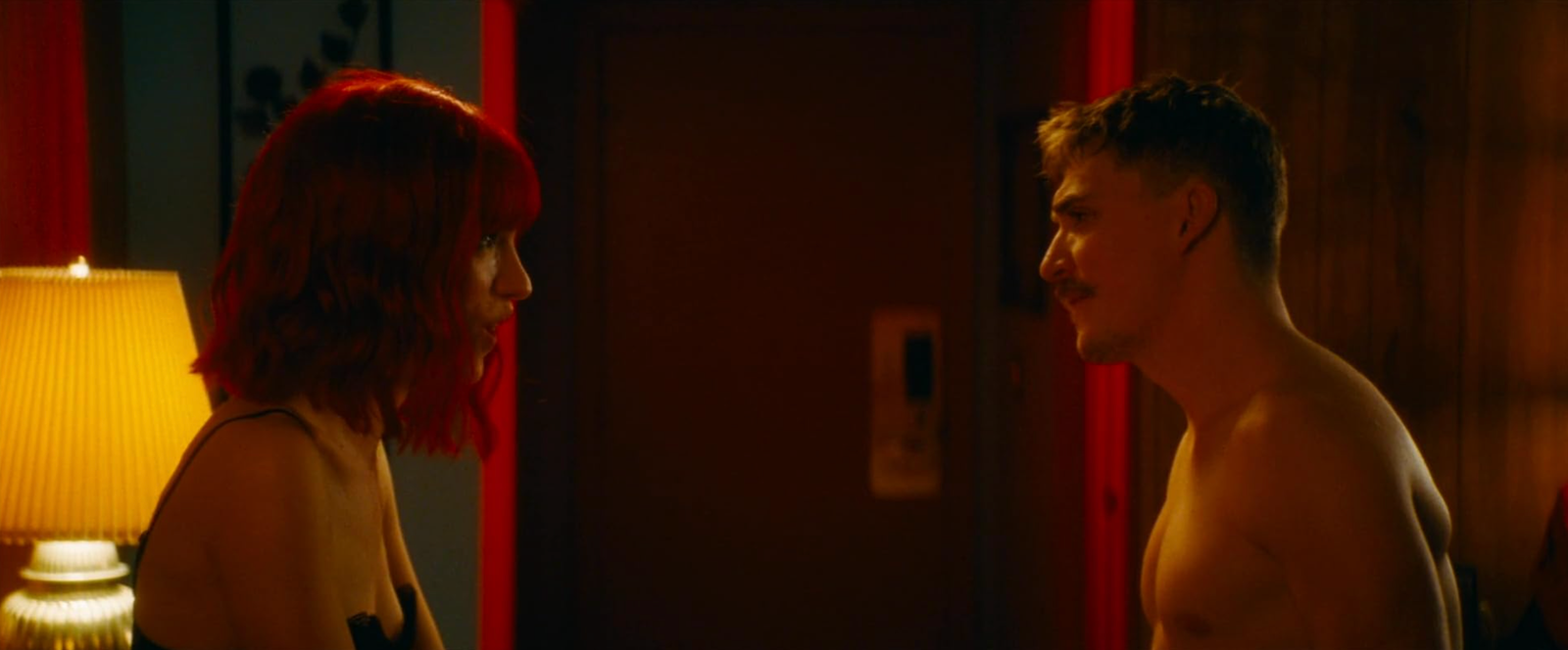 The Lady and the Demon standing face to face in a dimly lit motel room in Strange Darling