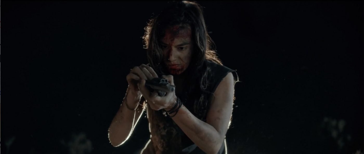 Bobbi examining Sheriff Bilstein's revolver with both hands, blood on her face