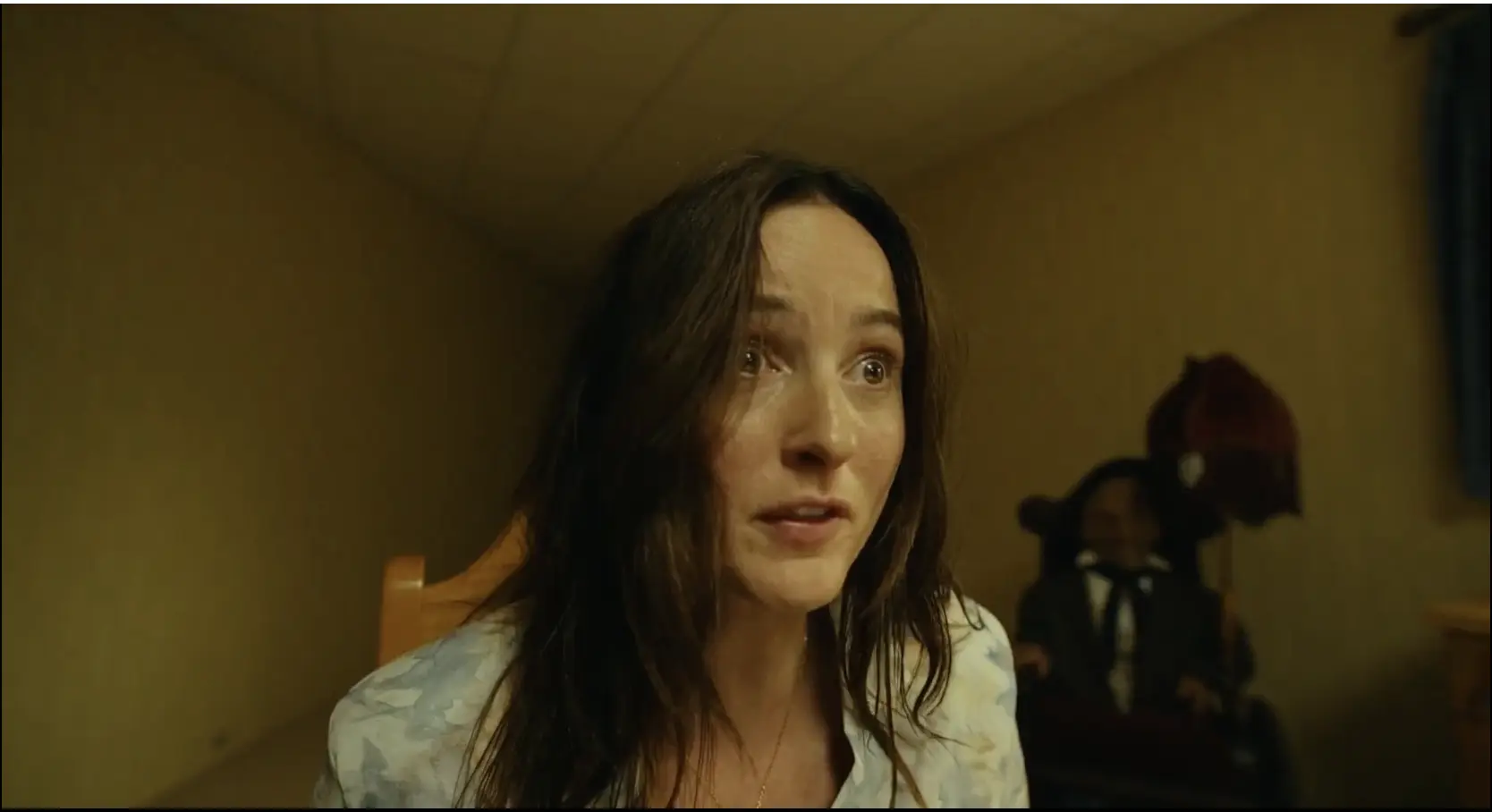 A frightened character in close-up with a motionless, ominous figure visible in the background