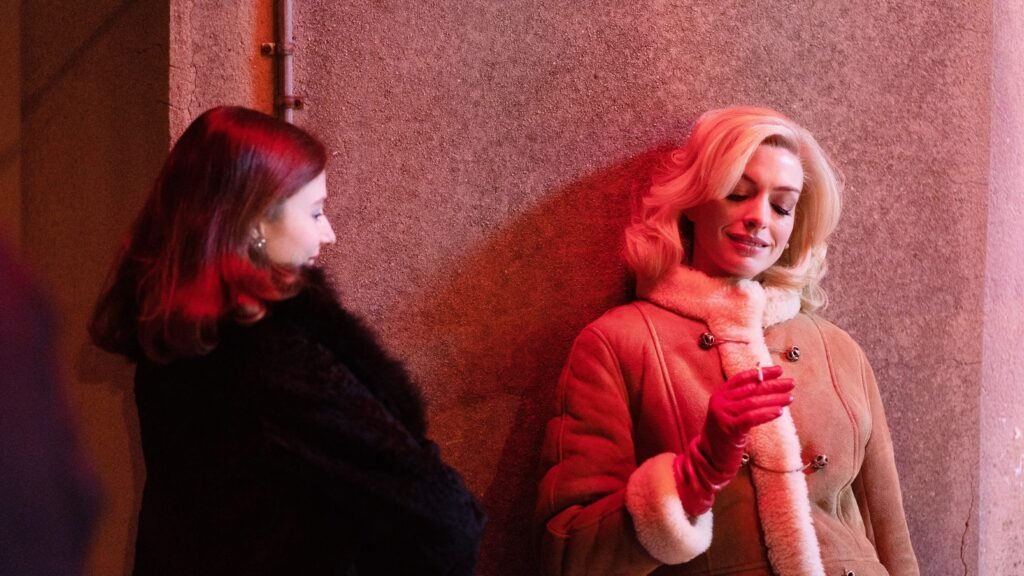 Rebecca and Eileen standing close together against a wall at night in Eileen (2023)