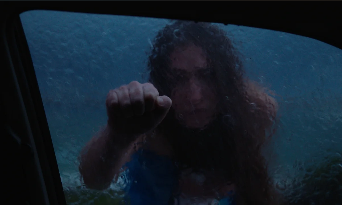 A woman knocking on a rain-soaked car window at night in You'll Never Find Me