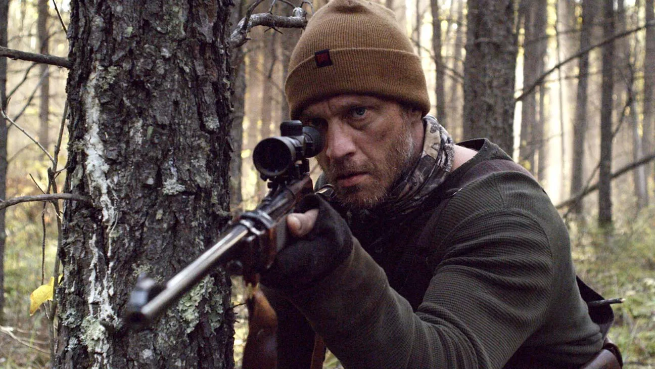 A trapper aiming a rifle in the woods in Hunter Hunter