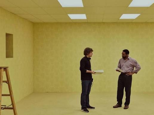 Behind-the-scenes photo of director Kane Parsons discussing a scene with Chiwetel Ejiofor on the yellow-walled Backrooms set