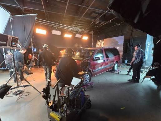 Behind-the-scenes view of a soundstage set built around a minivan