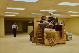 A huge chaotic pile of stacked furniture in the middle of an empty Backrooms room
