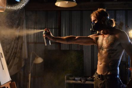 A shirtless artist spray-painting in a gas mask in The Devil's Candy