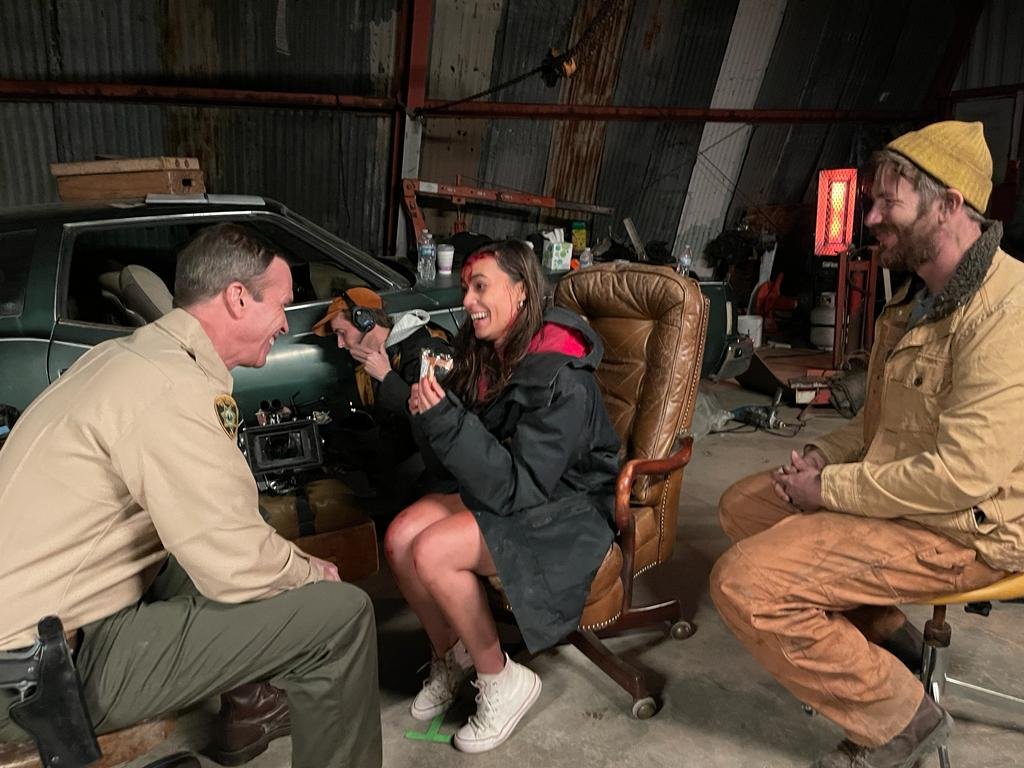 Crew members laughing together inside the dressed garage interior set for Blood Star